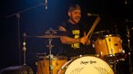 "Rival Sons"-Drummer im gelben Licht am Schlagzeug.
