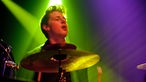 Drummer am Schlagzeug im lila-grünen Licht
