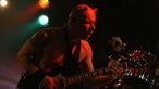 Gitarrist der Dirty Deeds 79' mit nacktem Oberkörper und angeklebten Teufelshörnern.