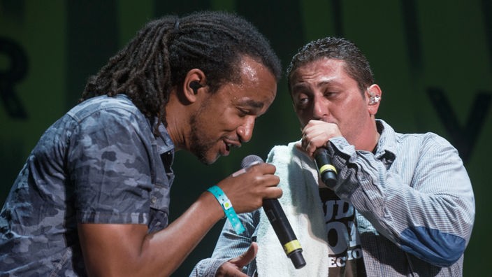 Die Dub Inc Frontmänner Aurélien "Komlan" Zohou und Hakim "Bouchkour" Meridja singen gemeinsam.