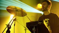 Drummer von Robots Don't Sleep im gelben Scheinwerferlicht