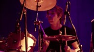 Schlagzeuger im schwarzen T-Shirt spielt konzertriert
