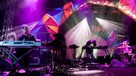 Die Band "Animal Collective" unter bunten Lichtbögen auf der Bühne.