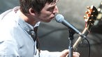 Noel Gallagher nochmals am Mikrofon und Gitarre spielend.