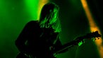 Gitarrist mit langen Haaren in grünem Bühnenlicht