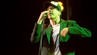 Sänger in grünem Licht singt in ein Mikrofon