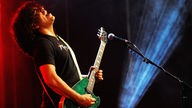The I.M.F´s Bandmitglied guckt hoch und spielt auf grüner Glitzergitarre