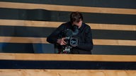 Ein Kameramann filmt von einer Tribüne aus.