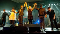 Zaz und ihre fünf Bandmitglieder stehen am Bühnenrand und halten sich an den Händen