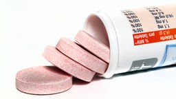 Mehrere Tabletten Nahrungsergänzungsmittel fallen aus einer liegenden Tube.