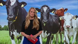 Die Moderatorin im SZ-Studio vor einem Bild von Kühen auf der Weide