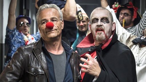 Max Ballauf (Klaus J. Behrendt) trägt die Pappnase, sein Kollege Freddy Schenk (Dietmar Bär) ein Dracula-Kostüm