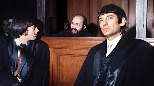 Die Rechtsanwälte Hans-Christian Ströbele (l) und Otto Schily unterhalten sich während eines Prozesses mit ihrem Mandanten Horst Mahler (M) in Berlin-Moabit im Oktober 1972.