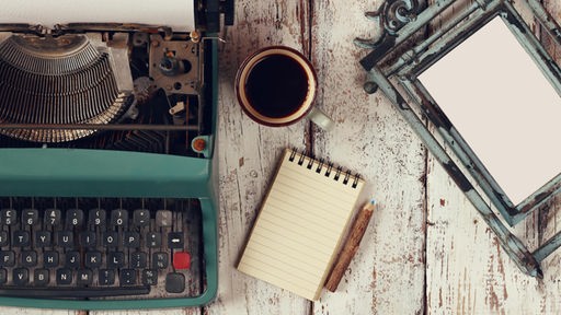 Schreibmaschnine, Notizblock und Tasse Kaffee