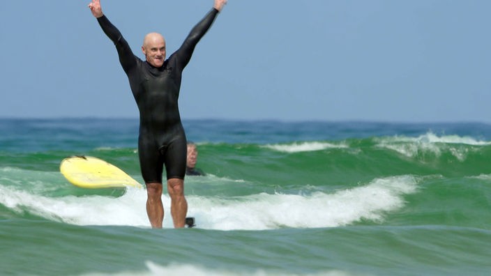 Aitor Francesena steht im Surfanzug auf einem Surfbrett inmitten der Wellen