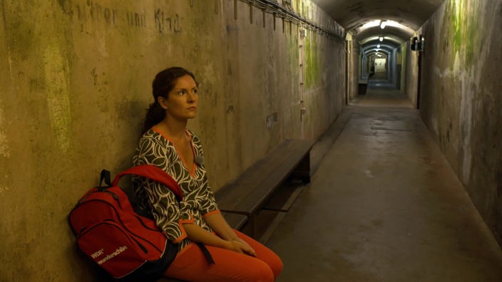 Anne Willmes sitzt auf einer Bank in einem Gang des Bunkerstollens