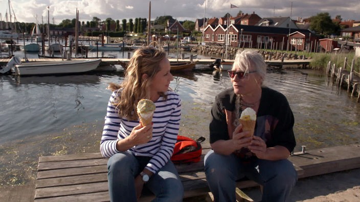 Tamina Kallert und Heike Arndt (r) sitzen auf einer Bank und essen eine Riesenportion Eis