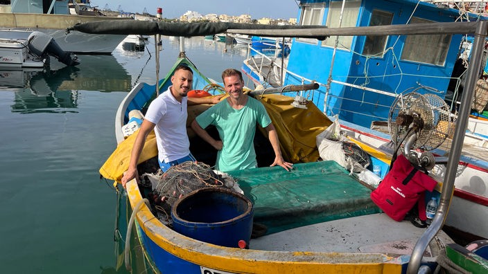 Daniel Aßmann und Fischer Andrew Grechauf auf einem Fischerboot im Hafen von Marsaxlokk