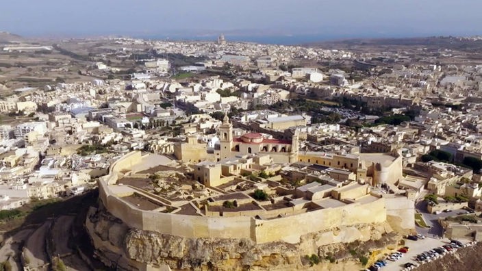 Festungsanlage mit Kirche und hohen Mauern auf einem Felsen inmitten der Stadt Gozo