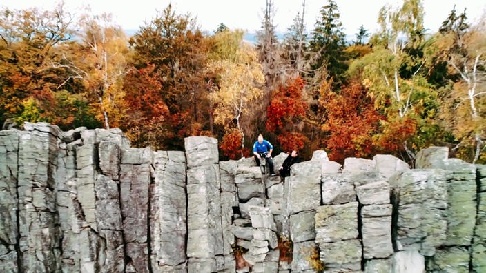 Zwei Kletterer sitzen auf einer hohen Felswand