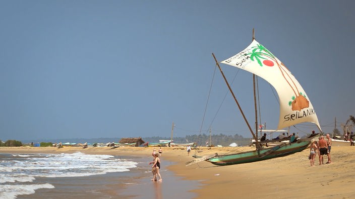 Am Strand von Negombo, im Vordergrund ein kleineres Segelboot auf dem Sand