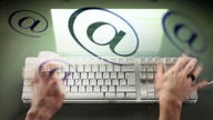 Eine Frau schreibt auf der Tastatur eines Computers, @ Symbole