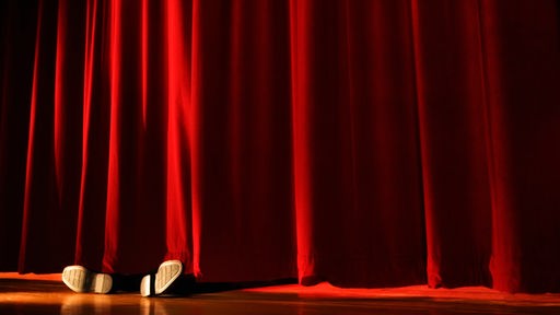 Füße hinter einem roten Theatervorhang