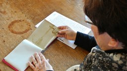 Heike Wolf sieht sich das Fotoalbum und den Bericht ihres Großvaters an.
