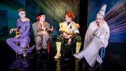 Szenenfoto: "Das Leben ist ein Clown" - auf der Bühne sitzen vier Schauspieler im Clownskostüm