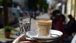 Ein Tablett mit einem Cafe und einem Glas Wasser