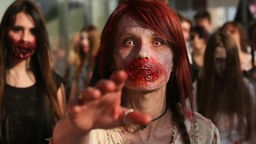 Eine Frau als Zombie kostümiert nimmt am einem Zombie-Walk teil 