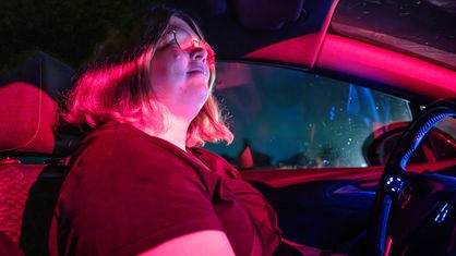 Eine Frau sitzt am Steuer eines Autos. Draußen ist es dunkel