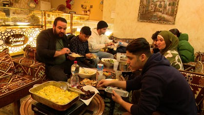 Um einen mit Essen gefüllten Tisch herum sitzen die Familie von Hanadi el Khatib und Mitarbeiter der Bäckerei beim Fastenbrechen