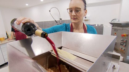 Frau leert Rotweinflasche in Nudelmaschine