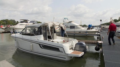 Ein weißes Motorboot liegt mit anderen Booten in einem Hafen.