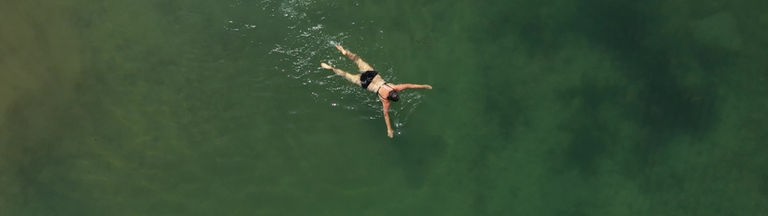 Luftaufnahme, eine Frau schwimmt in einem See