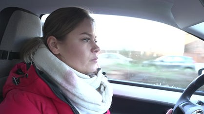 Profilansicht einer jungen Frau, die im Auto sitzt und auf Fahrbahn schaut