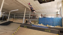 Cedric macht im Skatepark Wicked Woods einen Rückwärtssalto mit seinem Scooter