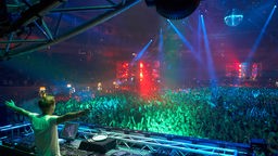 DJ Armin van Buuren steht bei der Mayday in der Westfalenhalle mit ausgebreiteten Armen vor einer Menschenmenge