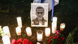Brennende Kerzen stehen um eine schwarz-weiß Portrait des verstorbenen Oppositionsführer Alexej Nawalny.