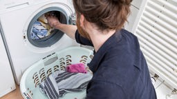 Ein Mann räumt eine Waschmaschine aus