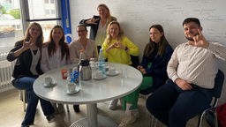 Mitglieder eines Vereins gehörloser Ukrainerinnen und Ukrainer in Wuppertal sitzen an einem Tisch. 