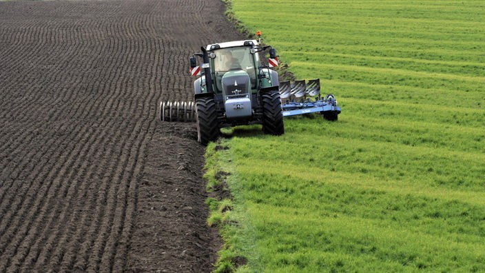 Ein Landwirt pflügt mit dem Traktor seinen Acker