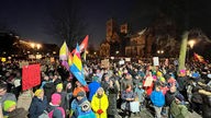Menschen versammeln sich in Münster zu einer Demo gegen Rechtsextremismus, viele Menschen halten Schilder und Fahnen