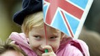 Ein kleines Mädchen hält eine kleine britische Flagge zur Begrüßung von Elizabeth II.