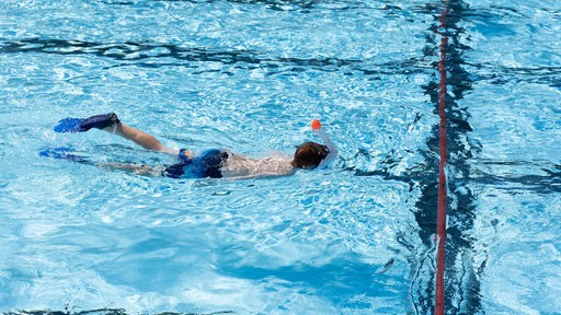 Ein Schwimmer taucht durch das Becken im Freibad
