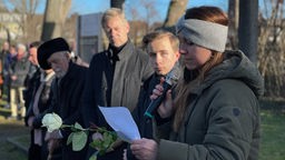 Eine Person hält bei der Gedenkveranstaltung im KZ Buchenwald Außenlager Witten Annen eine Rede, andere Personen hören interessiert zu