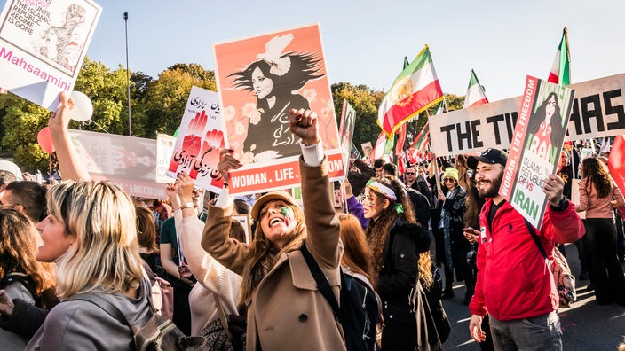 Menschen die demonstrieren, auf ihren Plakaten oft der Slogan "Frau Leben Freiheit".