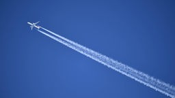 Ein Flugzeug am Himmel mit Kondensstreifen dahinter