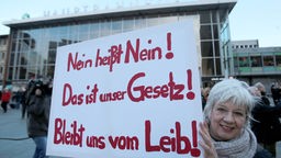 Frau mit Poster vor Hauptbahnhof "Nein heißt Nein! Das ist unser Gesetz! Bleibt uns vom Leib!"